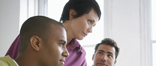 Woman instructing two men on a computer